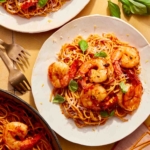 Tomato butter pasta with shrimp being served from a skillet.