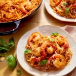 Two plates of tomato butter pasta with shrimp.