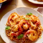 Two plates of tomato butter pasta with shrimp.