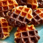 Liege waffles dipping in chocolate on a platter.