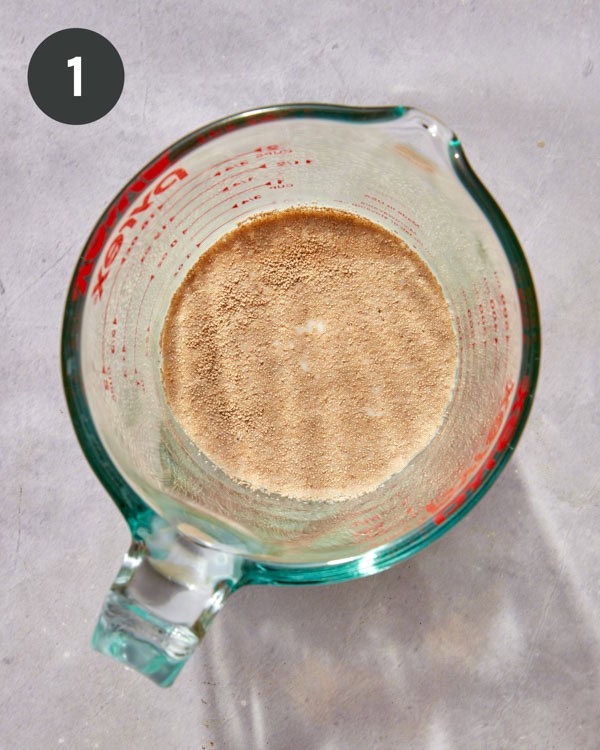 A measuring cup with yeast and warm milk.