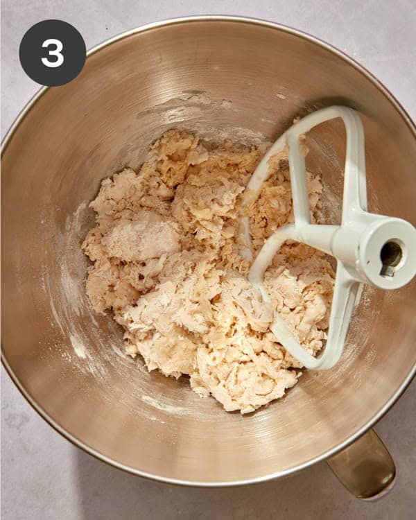 The shaggy dough of liege waffles in the well of a stand mixer.