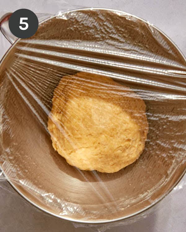 A ball of dough for liege waffles with plastic wrap over the bowl.