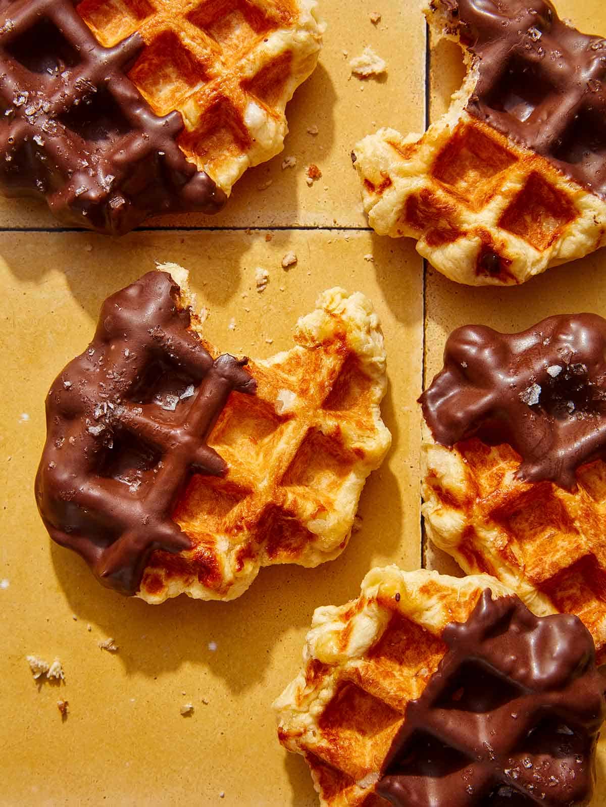Partially eaten liege waffles with bites taken out of them on a kitchen counter.