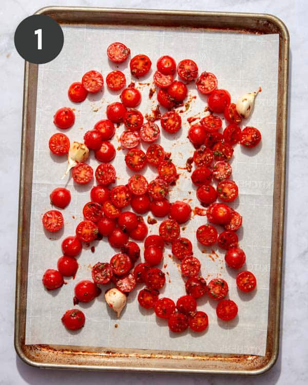 Tomato and garlic on a baking sheet with parchment.