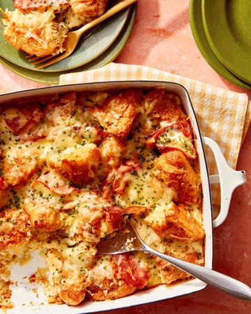A croissant bake with a spoon it in serving onto plates.
