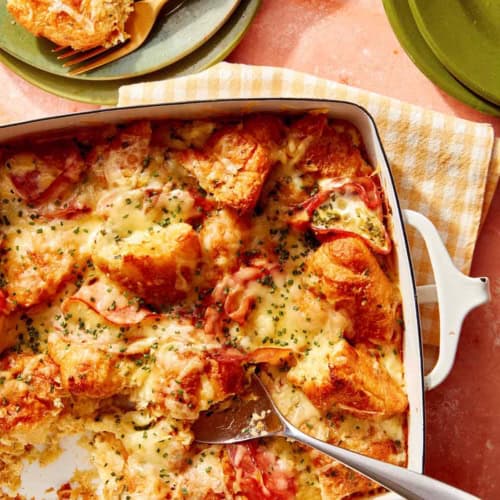 A croissant bake with a spoon it in serving onto plates.