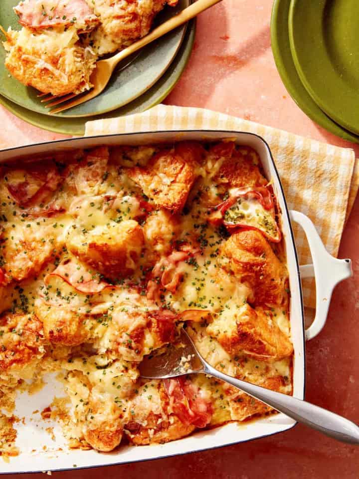 A croissant bake with a spoon it in serving onto plates.