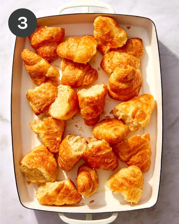 A baking dish filled with torn croissants.