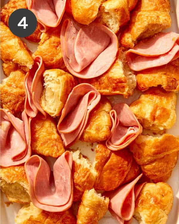 A baking dish with croissants and ham.