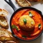 Fried burrata over romesco sauce in a skillet with bread.