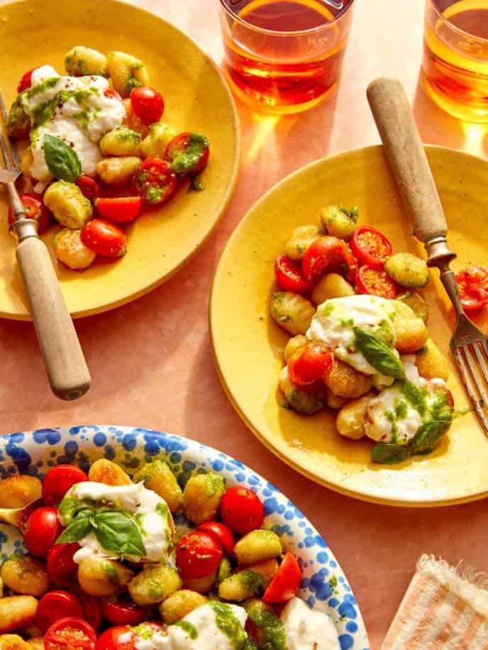 Plates with pan fried caprese gnocchi on them and forks.