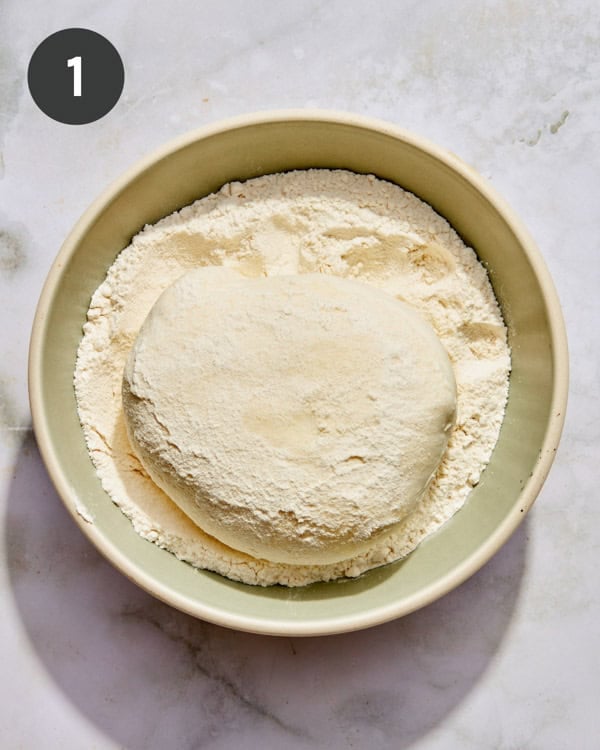 A burrata ball being dredged in flour.