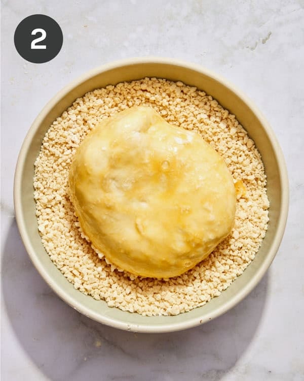 A burrata ball being dredged in panko.