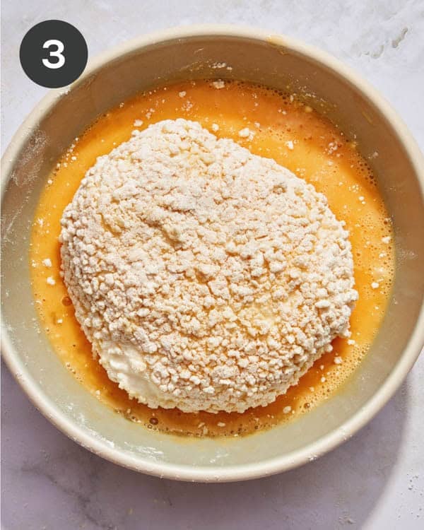 A burrata ball being dredged in panko.