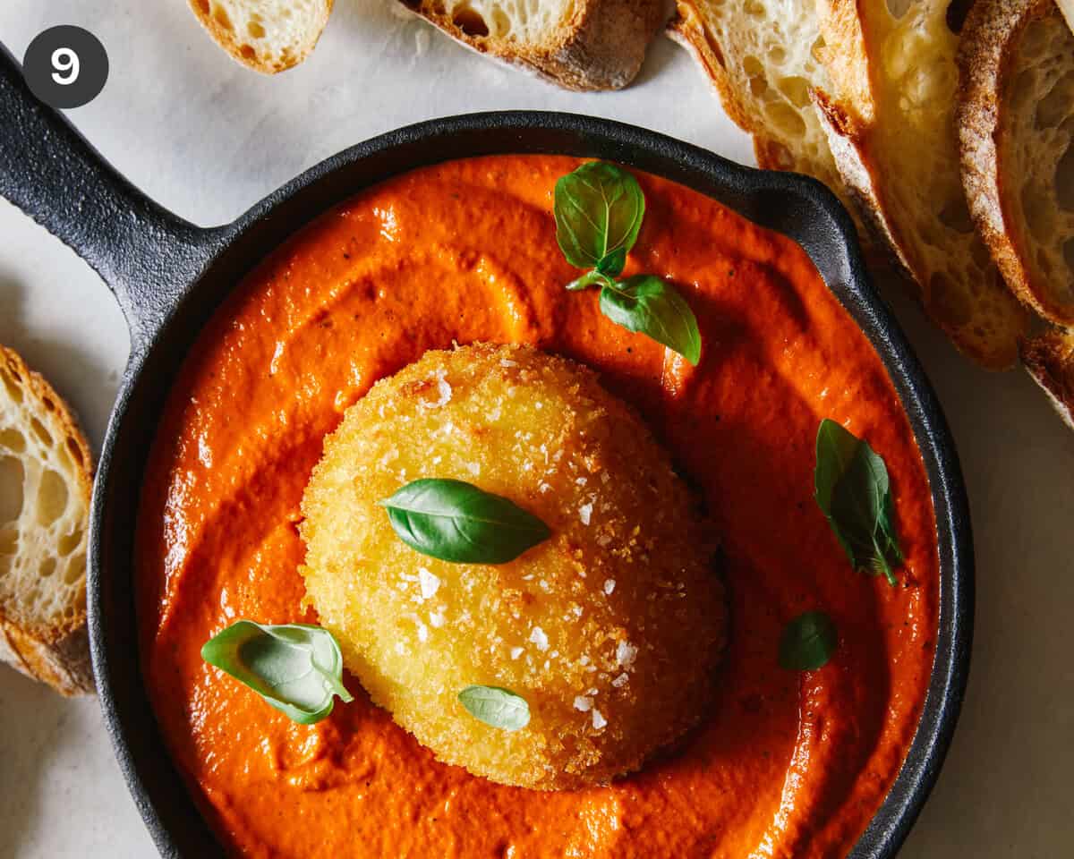 Fried burrata over romesco sauce in a skillet with bread.