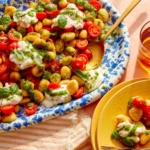 Caprese gnocchi that was pan fried on a platter with some being served onto plates.