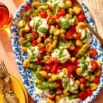 Caprese gnocchi on a platter with serving dishes on the side.