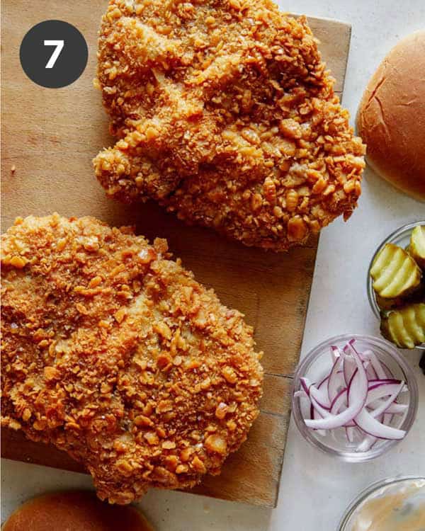 Pork cutlets on a cutting board with toppings next to it.