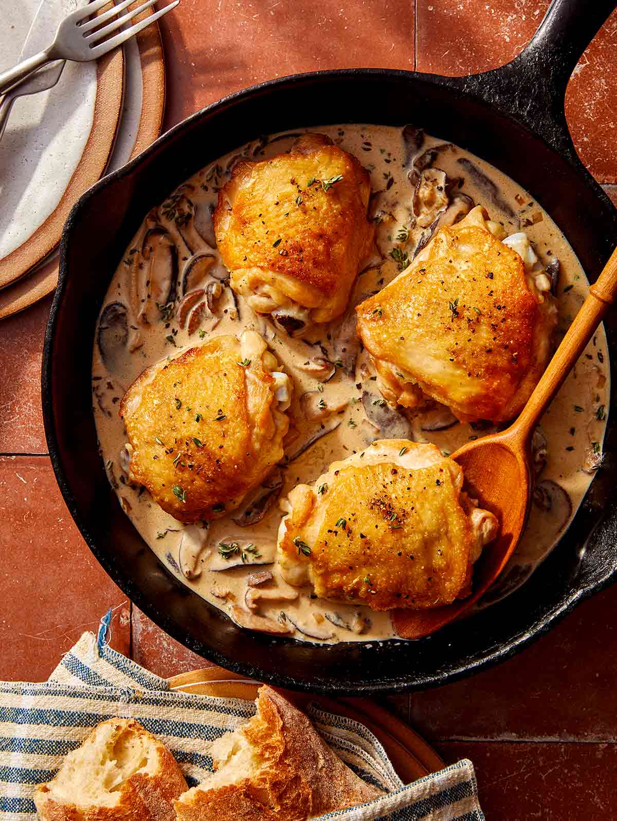 Crispy chicken thighs in a skillet with a creamy mushroom sauce.