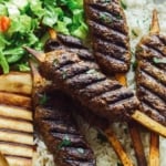 Lamb kofta skewers on a platter with pita and rice.