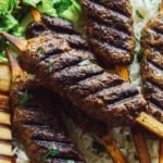 Lamb kofta skewers on a platter with pita and rice.
