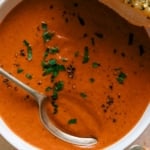Tomato soup recipe in two bowls with garlic bread on the side.