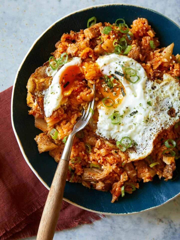 A close up of kimchi fried rice in a bowl with a fork.